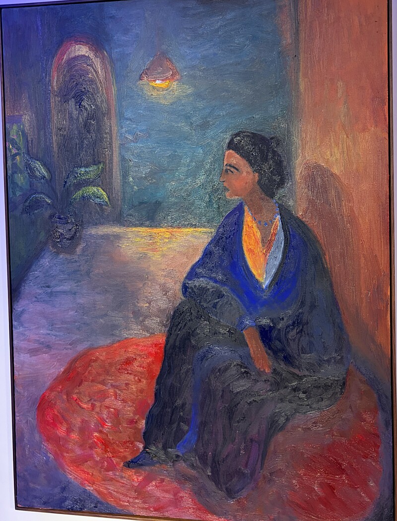 Oil painting: a woman in a cobalt shawl seated on a red rug in a teal and terracotta interior, a lamp burning above her.